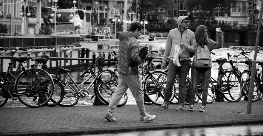 two people walking along a street with bicycles behind them