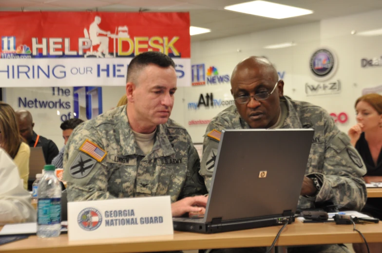 two soldiers are looking at a laptop