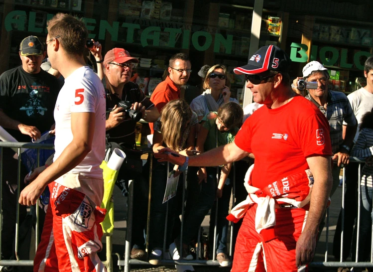 two men in red are shaking hands with an official