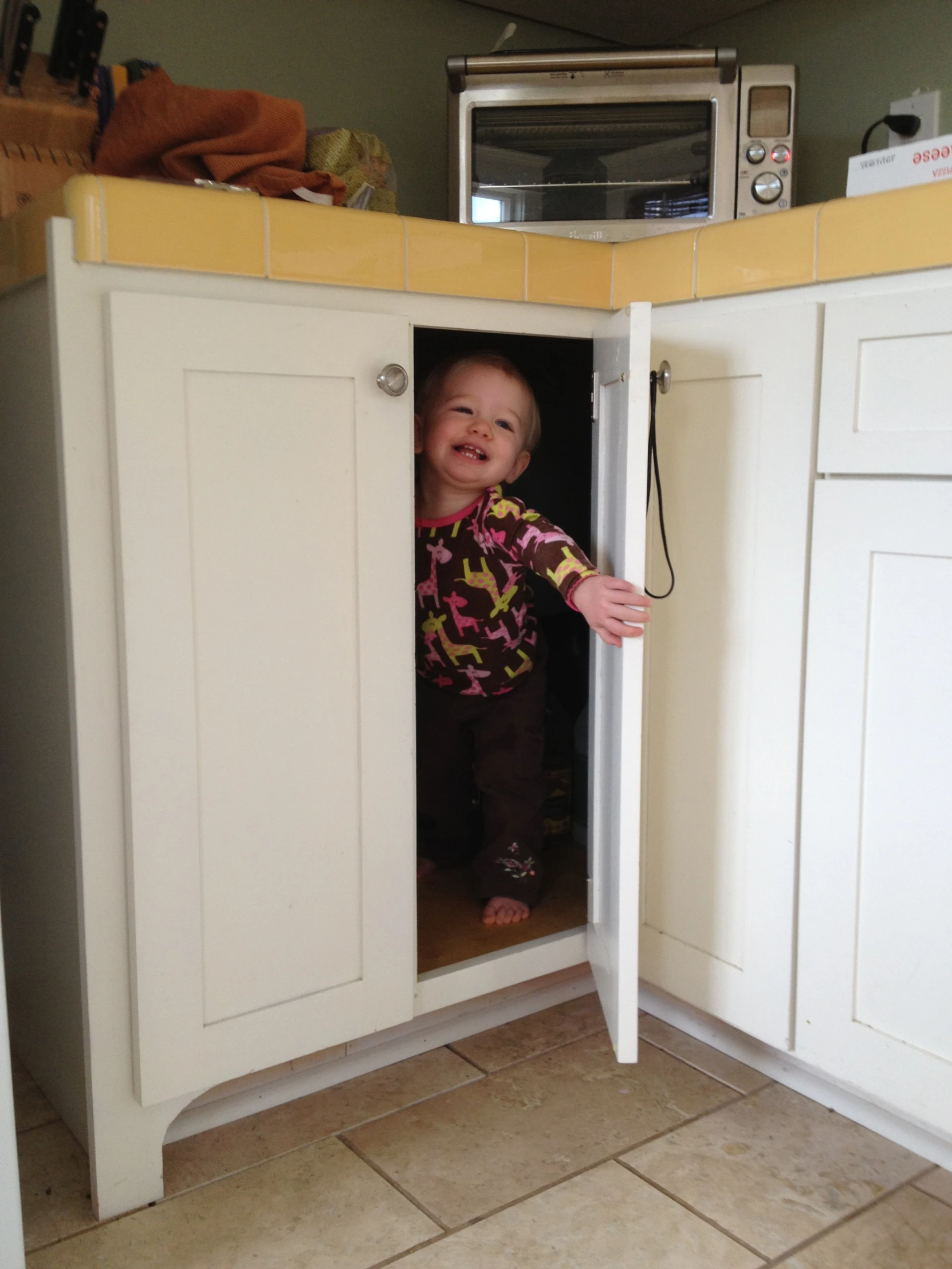 the baby is inside of a kitchen cupboard