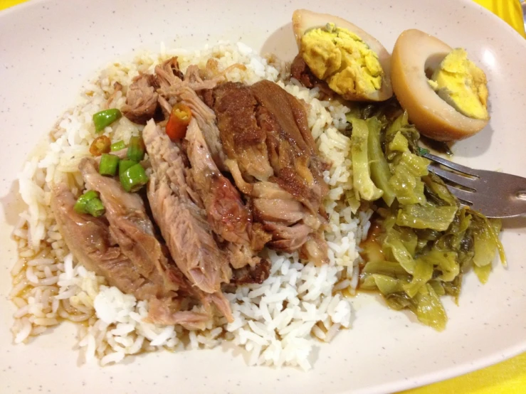 a white plate topped with rice and meat