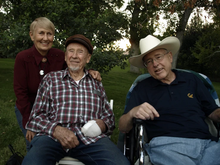 an older man is sitting in a chair while a woman holds soing behind him