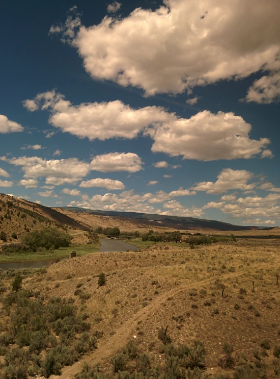 an empty dry grassy plain with a stream in the foreground