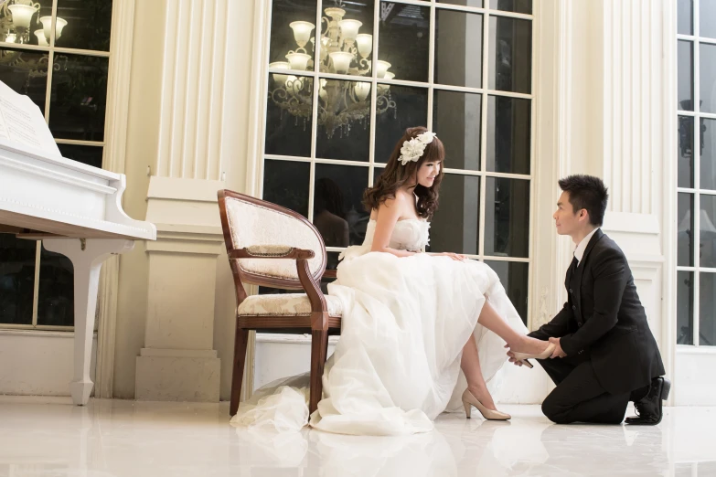 the bride and groom sit in front of the piano