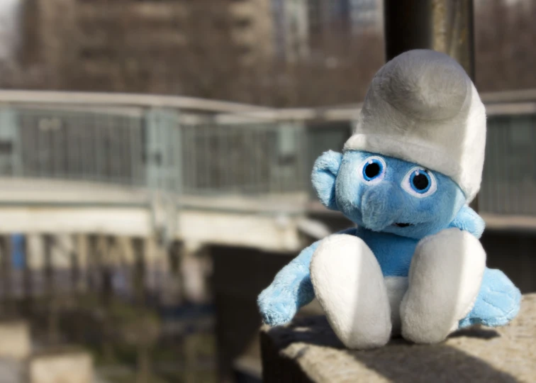 a small blue stuffed animal sitting on top of a wall