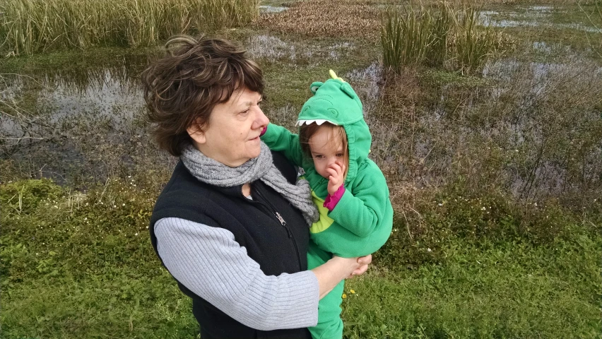 a woman holding a baby in a frog costume