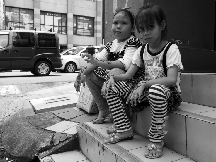 two children sitting on the step of a building in front of a van