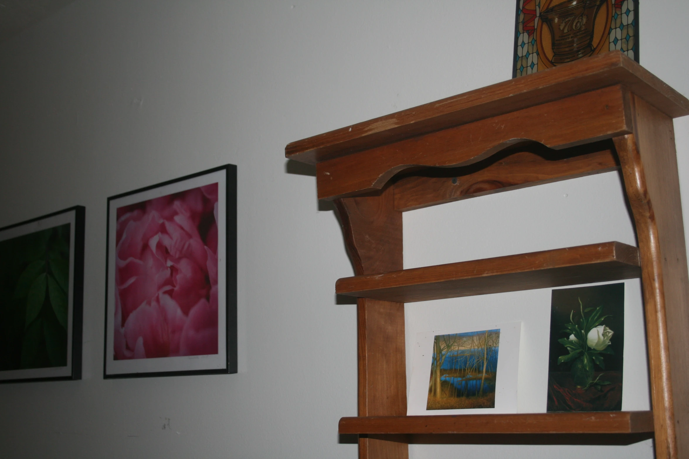 a shelf with three paintings hanging up on the wall