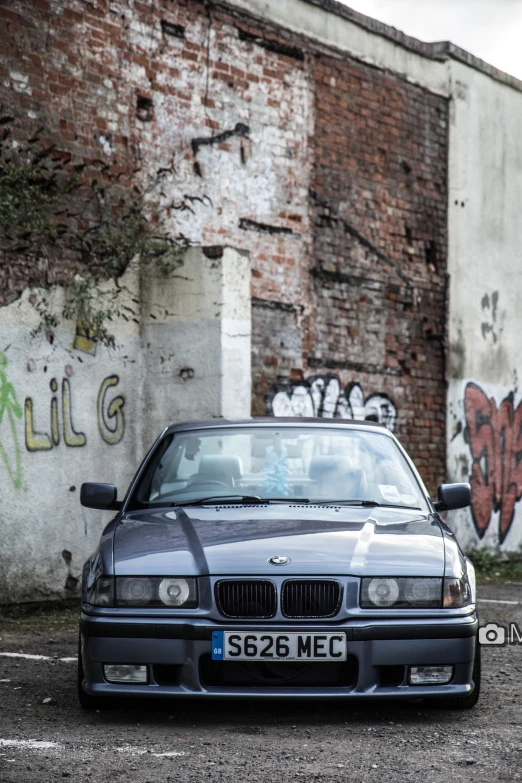 an old bmw is parked next to a large brick building