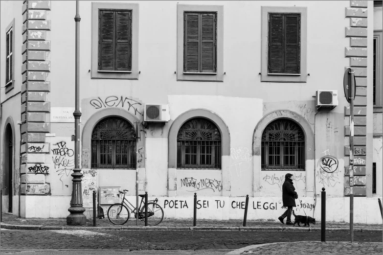 the man walks past an old building with graffiti on it