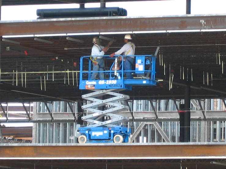 two men on a scissor working on a building