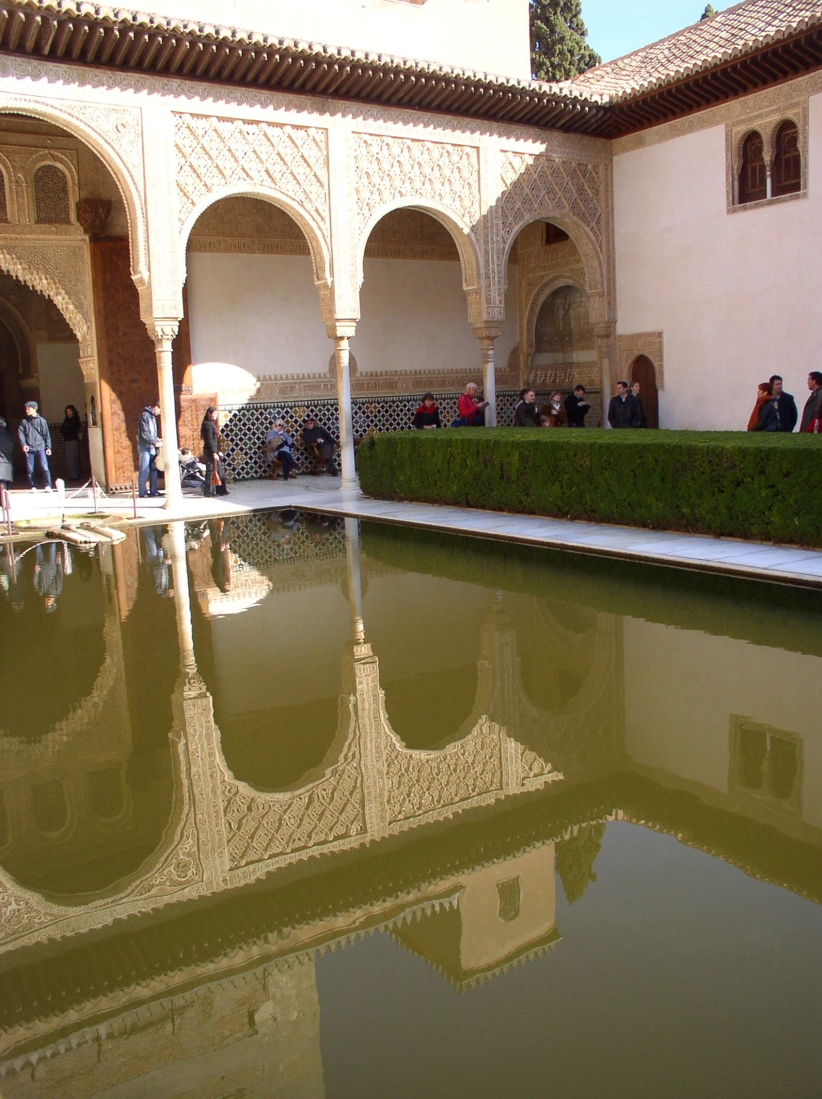 people are standing around a pool in a courtyard