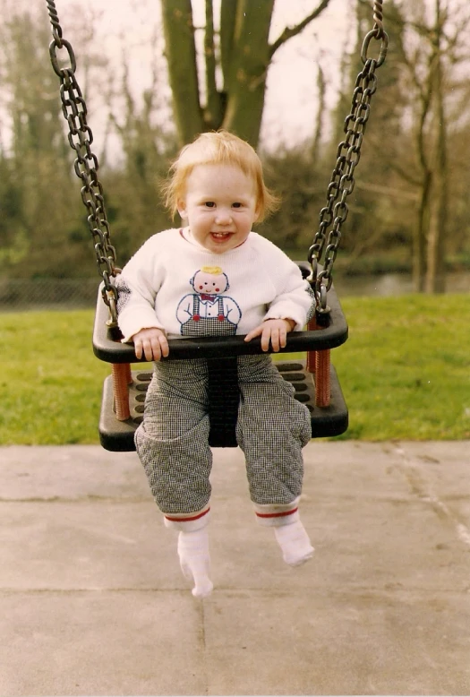 a young child sits in a swing laughing