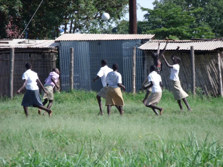 five young women are playing soccer in an enclosed field