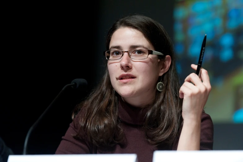 a woman holding a pen to her right ear