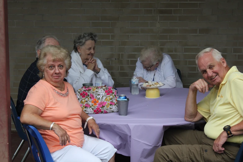 there are four people sitting at the table eating cake