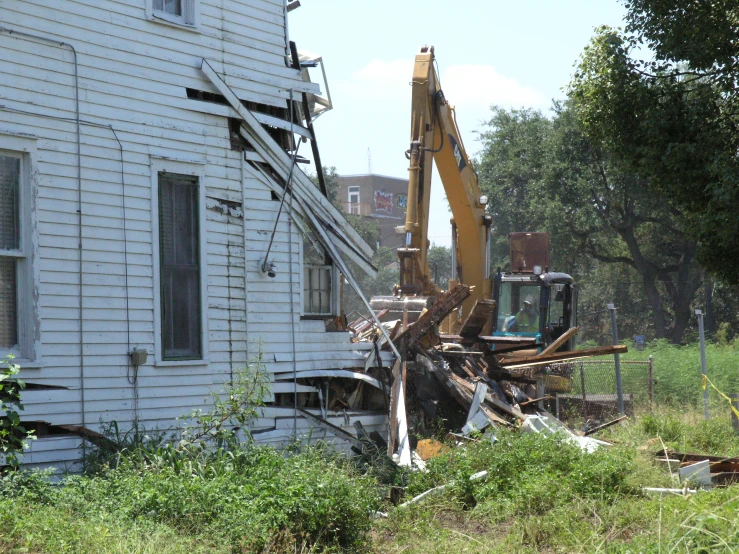 a backhoe digging out rubble from a house