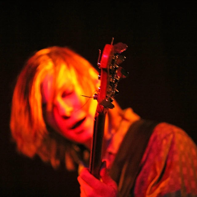 a woman holding a guitar with yellow light