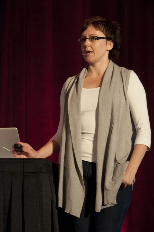 a woman giving a speech at a podium with a screen