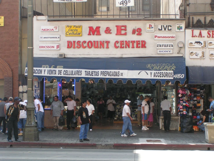 a group of people standing outside of a store on the corner