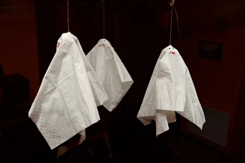 three folded white cloths hanging in the dark