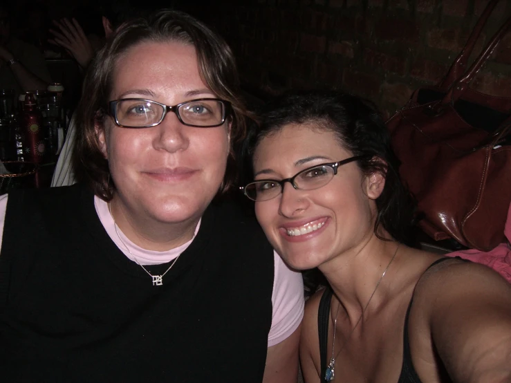 two women pose for a po while one of them wears glasses