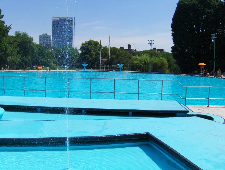 a fountain is seen at the center of a pool in a park