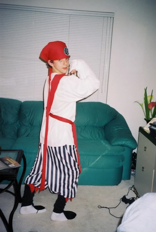 a boy dressed up as an evil pirate standing in front of a couch