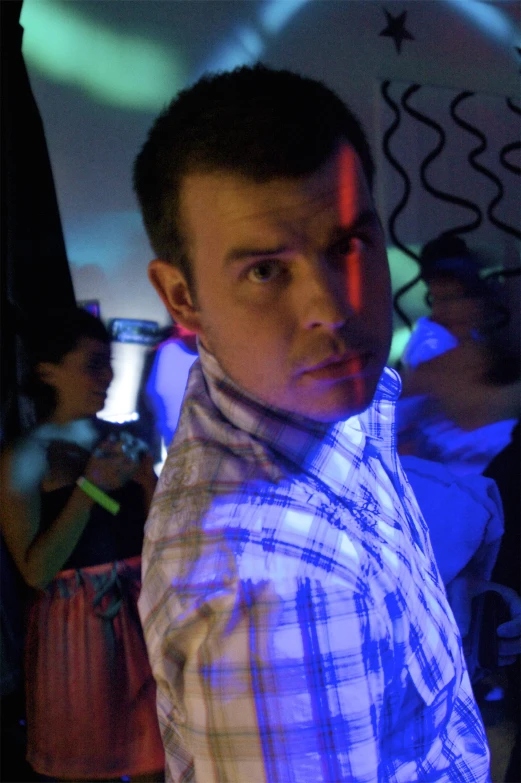 a man standing in a dark room in front of a person with neon light