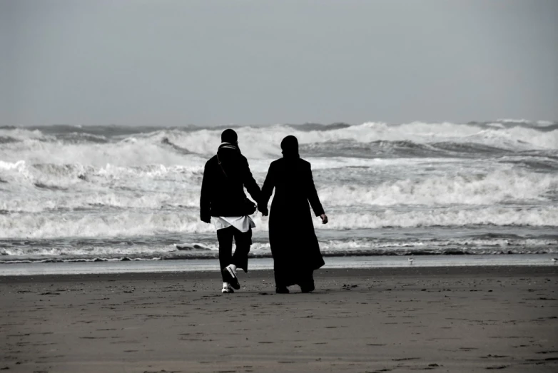 a couple of people are walking on a beach near the ocean