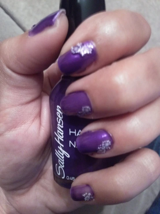 a woman's nails with purple nail polish and white flowers