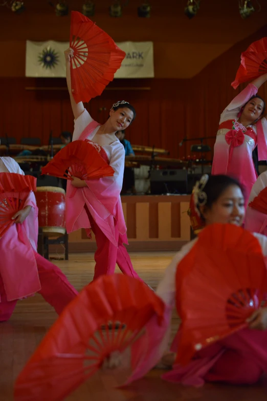 a group of young ladies holding red parasols while standing on stage