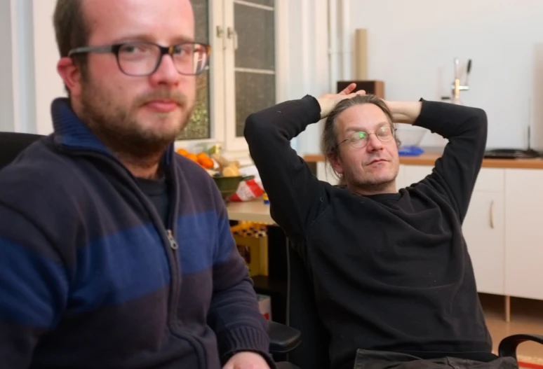 two people that are wearing glasses while sitting down