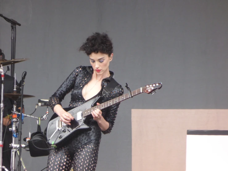 a woman with short hair standing next to a guitar and microphone