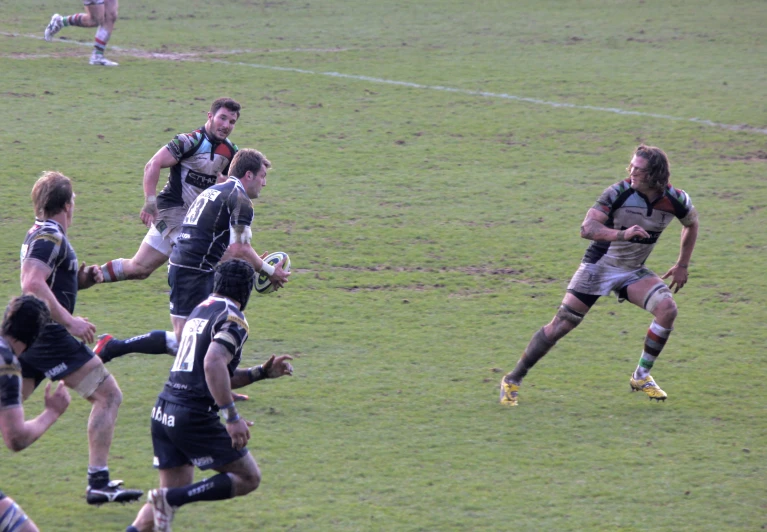 a rugby player runs with the ball past two other players