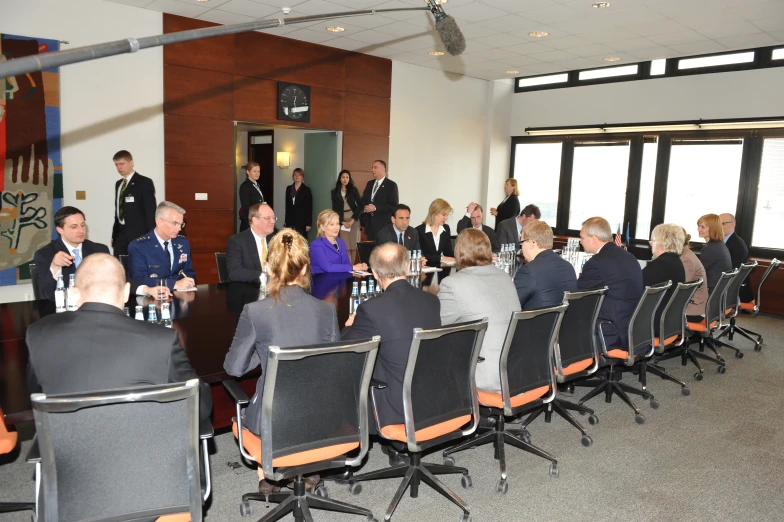 a large group of people sit at desks in front of large windows