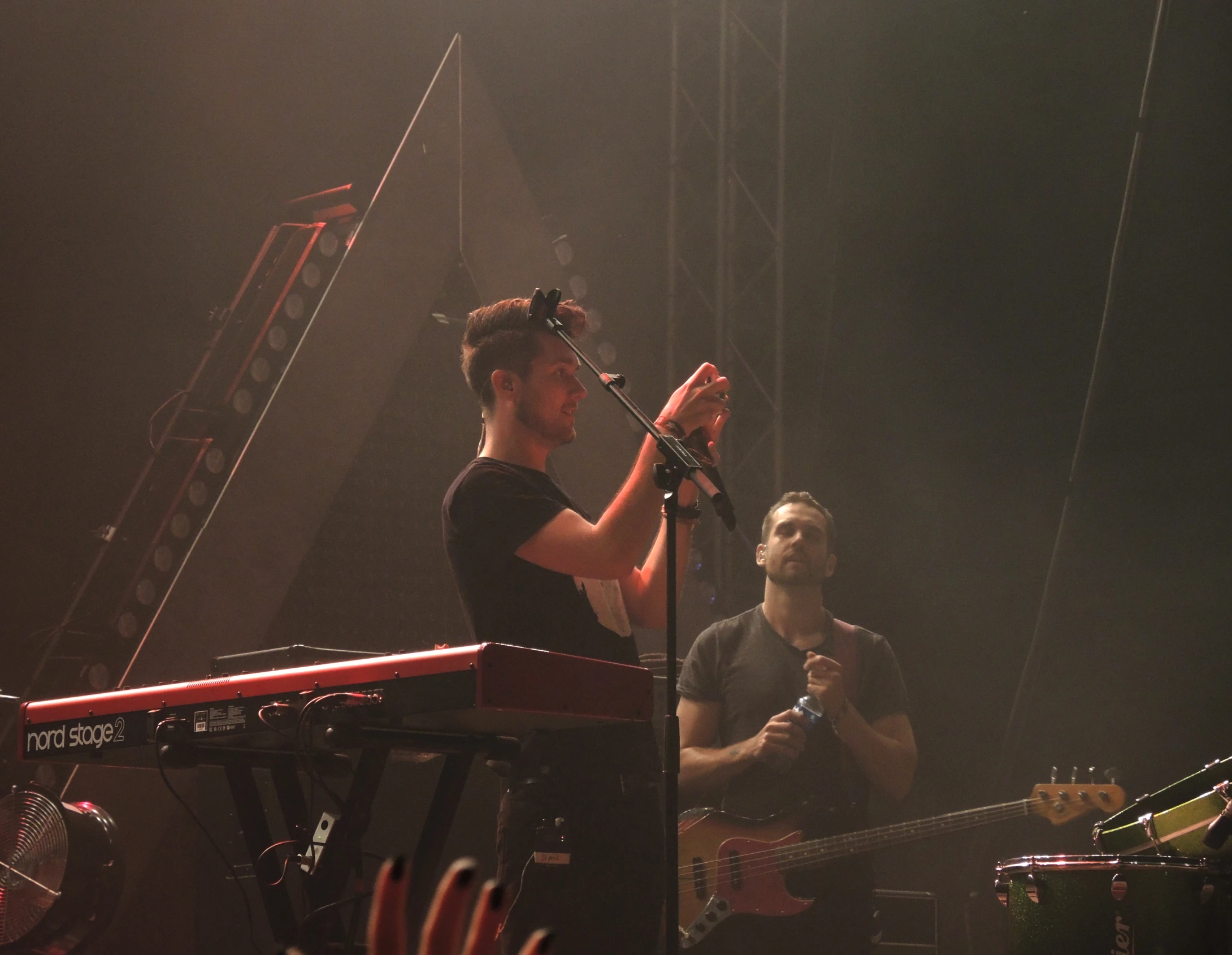 two men singing into microphones in front of a keyboard