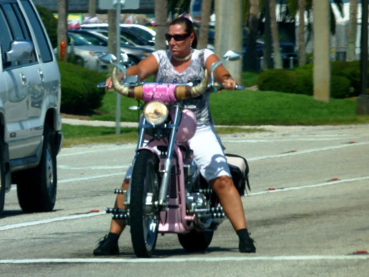 a woman with no shoes on is riding her pink motorcycle