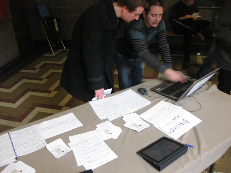 two people standing at a table with papers on top of it