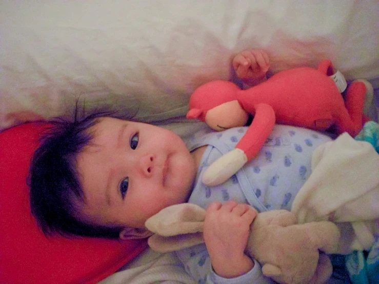 a baby lying on its back and holding onto the doll