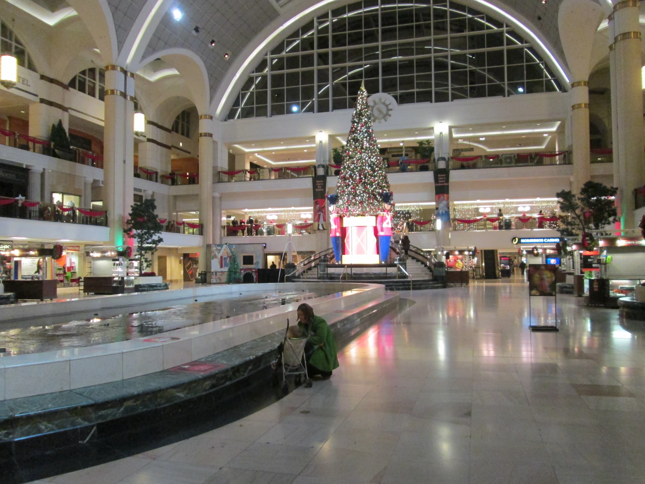 a woman sits by the edge of an empty shopping mall