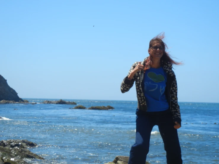 woman taking po with cellphone standing near ocean