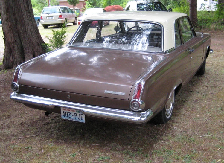 an old brown car is parked in the grass