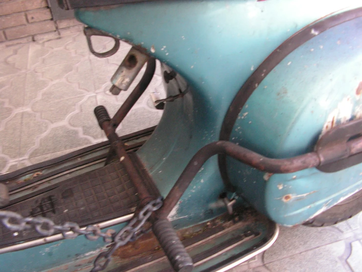 an old broken blue car with chain and handlebars