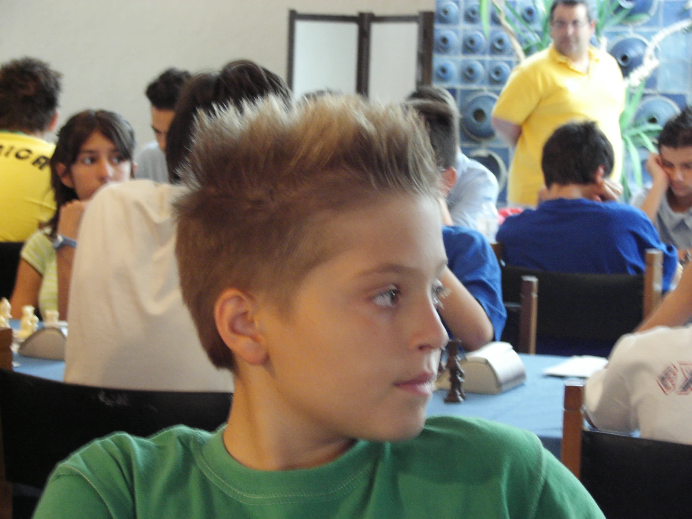 a boy with a mohawk sits in a restaurant