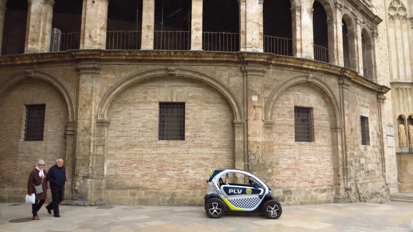 an electric vehicle sitting parked next to a stone building