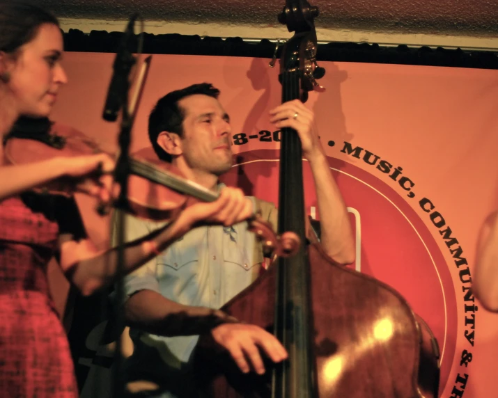 a man is playing a violin and standing near another man