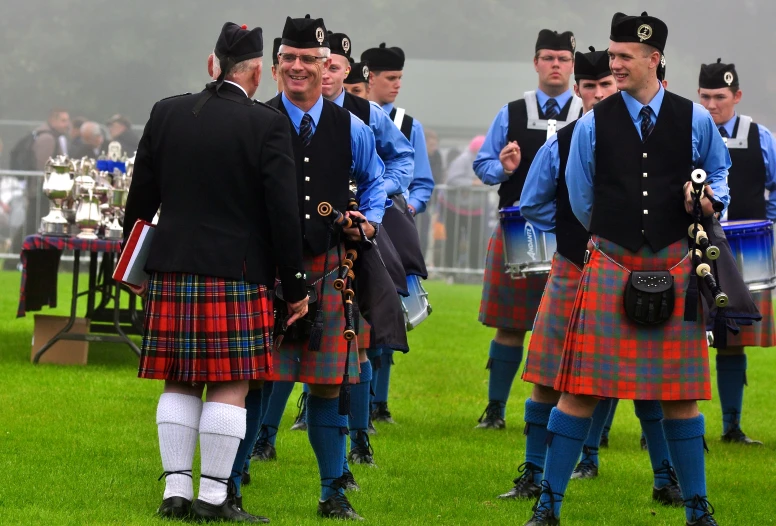 a group of men in kilts dancing with people watching