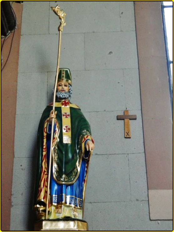 a small statue of a man holding a golden scept and a sword in a corner