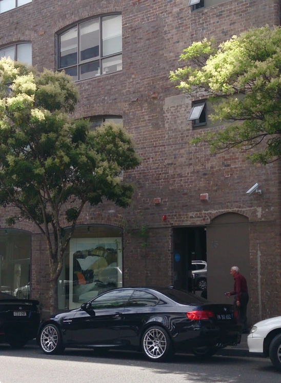 two cars parked on a street in front of a tall building